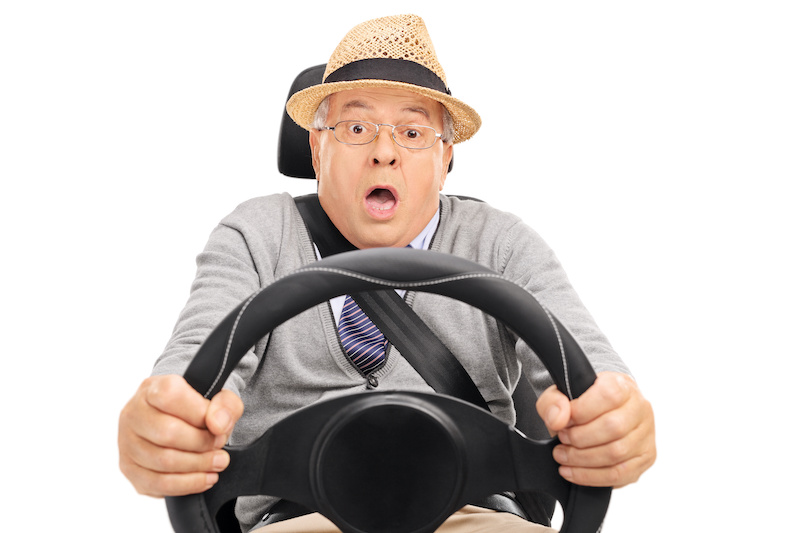 Scared senior holding a steering wheel and pressing the brake pedal to avoid a car crash isolated on white background