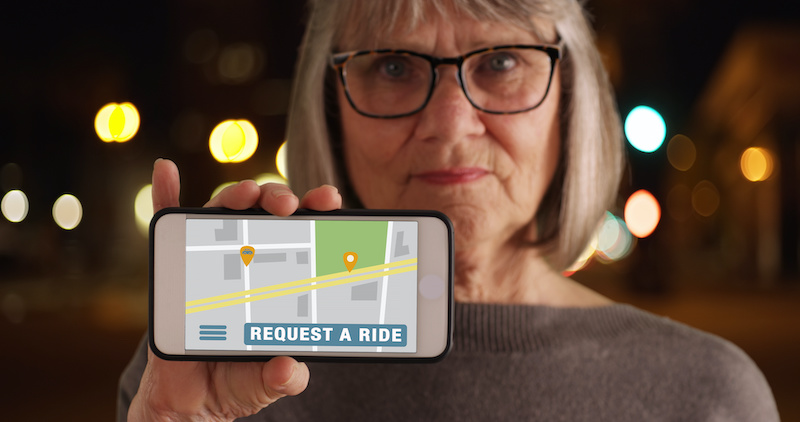 Old woman showing phone screen to camera with rideshare application open