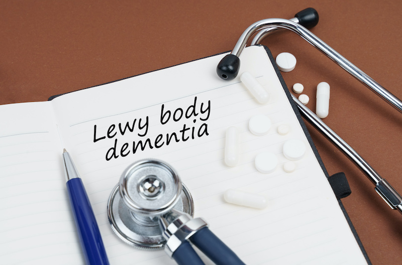Medicine and health concept. On a brown surface lie pills, a pen, a stethoscope and a notebook with the inscription - Lewy body dementia