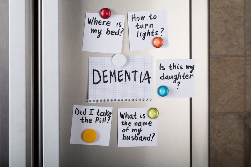 Closeup of dementia note with various reminders attached with magnetic thumbtacks on metal