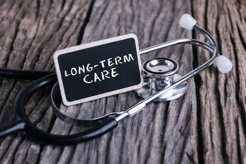 Medicine concept. Blackboard with word LONG TERM CARE and stethoscope on wooden background.