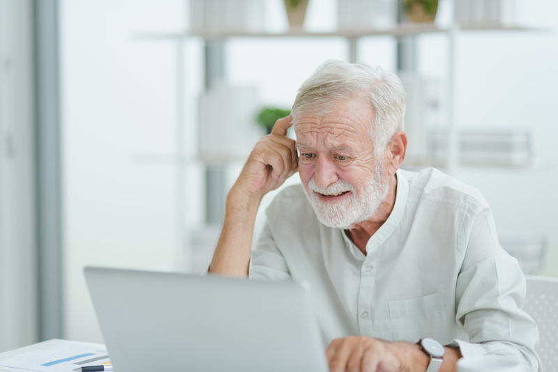 The senior elderly man in white casual outfit work from home sitting and get confuse from work in a modern workplace room.