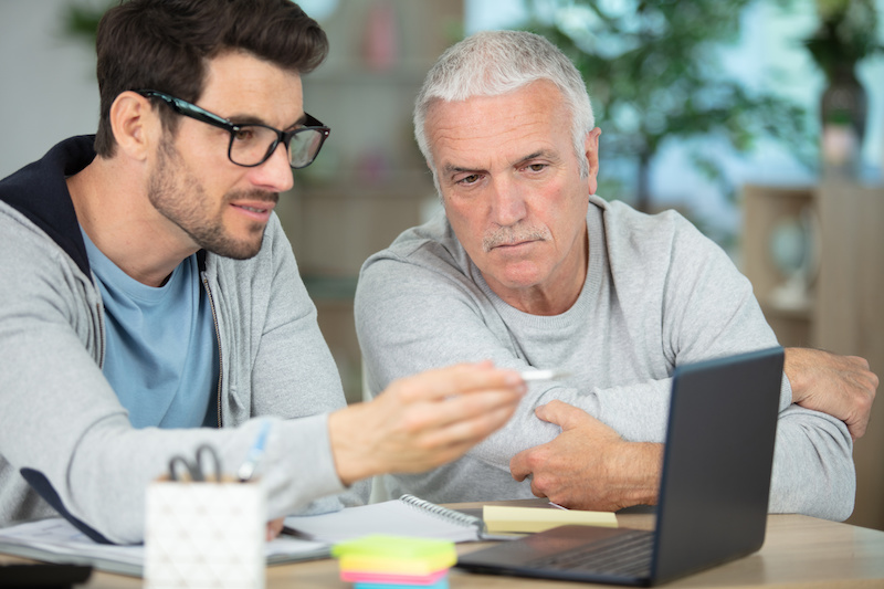 father and mature son looking at pc together