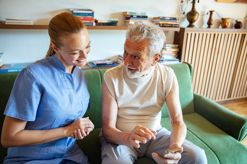 Female caregiver helping senior man at home