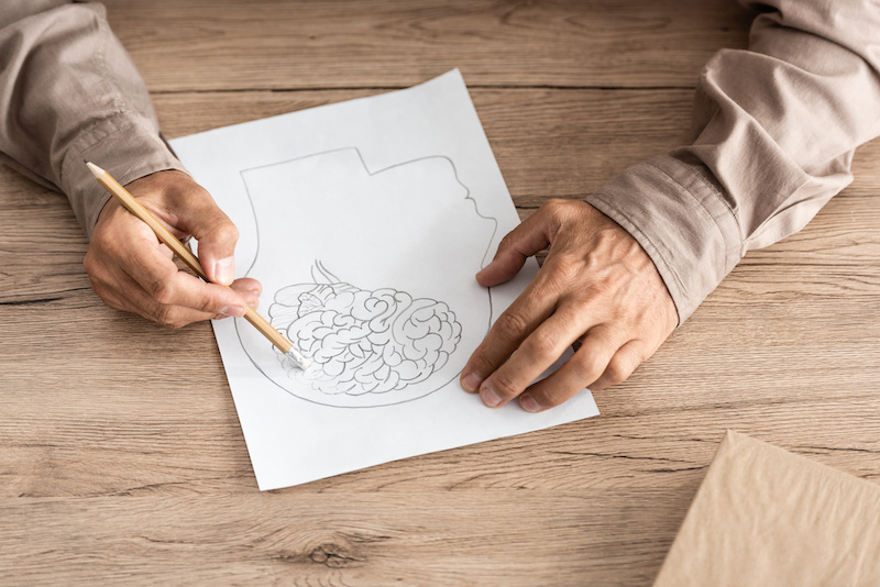 cropped view of retired man with alzheimer disease drawing human head and brain