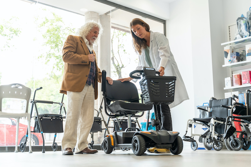 Older man in an orthopedic products store trying out an electric scooter