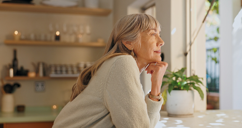 Window, smile and elderly woman with thinking at home for retirement, satisfaction and peace on weekend. Relax, senior person and calm with idea for reflection, mindfulness and good memory in house.