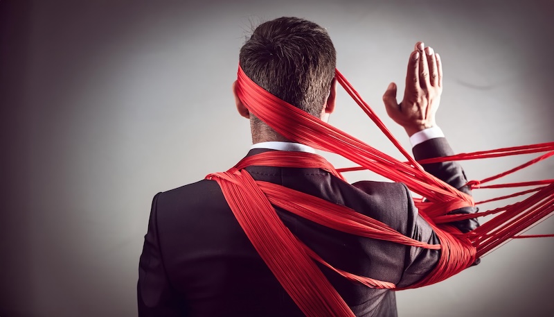 Businessman tangled in a web of red tape symbolizing financial bureaucracy