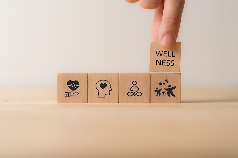 Wellness concept. Wooden cube blocks with health, mindfulness, mental health, happiness, financial stability and growth icons on white background. Balance, integration in achieving overall wellbeing.