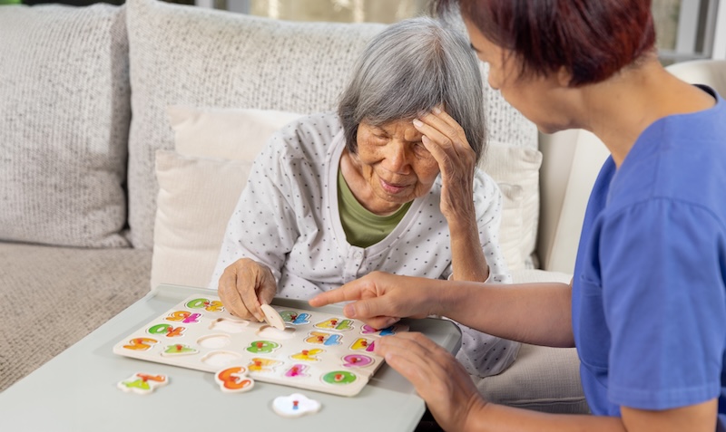 dementia care Nurse in nursing home helping a senior woman with number puzzle.  . Dementia, Alzheimer's disease concept