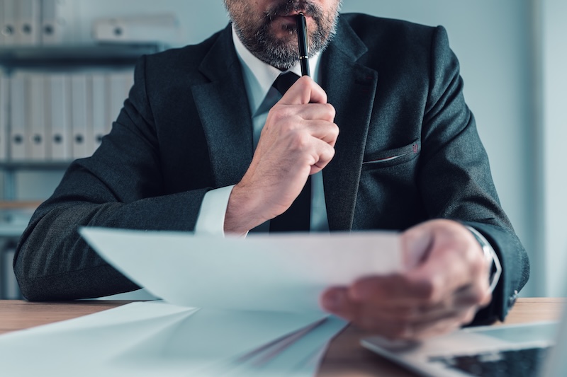 Fiduciary, agent carefully reading business papers in office, selective focus