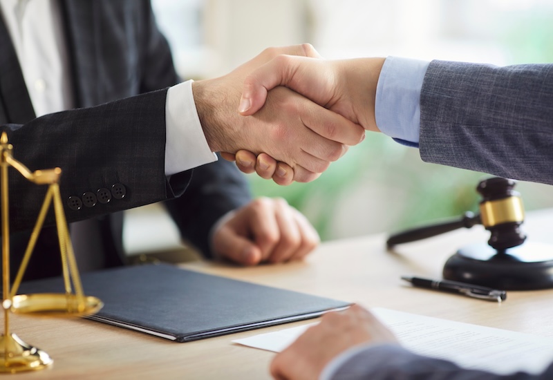 Lawyer or attorney shakes hand with client during office meeting, focusing on collaboration and deal in a professional setting with a sense of partnership and legal agreement and contract signing.