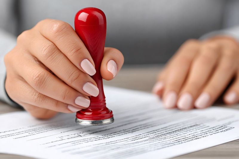 Female notary public is applying a stamp to a legal document, validating a contract or agreement