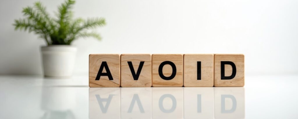 Wooden blocks spell the word AVOID. A small plant sits on the left side of the frame. This image represents caution, risk or making a choice to not do something.