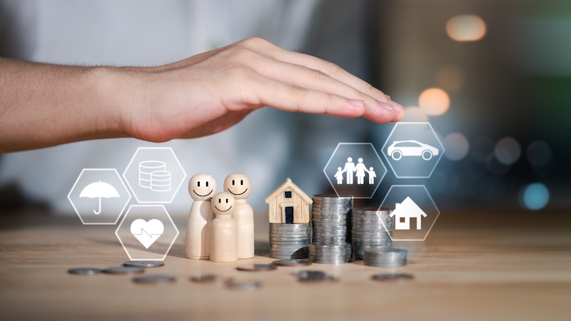 Financial family planning concept with coins, wooden figures, and insurance icons under protective hand, symbolizing budgeting, future savings, financial security, and protection of health and assets.