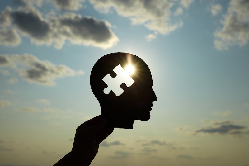 Concept of a human head with a puzzle in the middle. Finding a solution in the human brain. Concept of cognitive rehabilitation in Alzheimer's disease and dementia patien. Mental health.