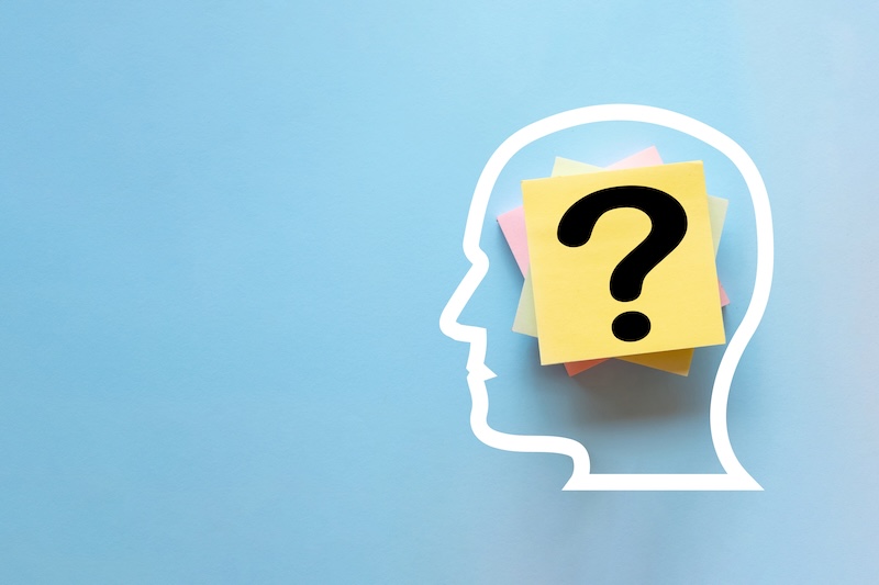 Human head silhouette with sticky notes and a question mark inside on a blue background with copyspace.,Concept represents thinking, confusion, memory loss, mental health, and brainstorming.