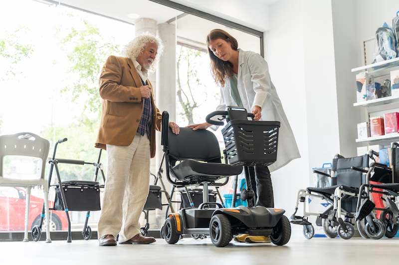 Older man in an orthopedic products store trying out an electric scooter