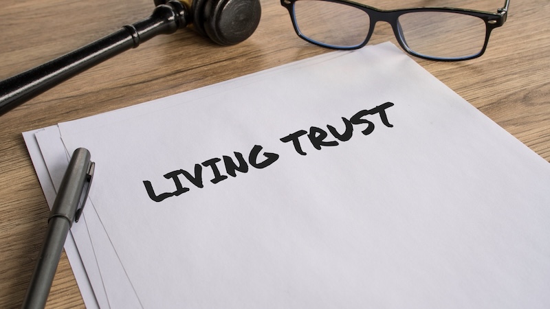 Living Trust legal document on wooden desk with gavel and glasses