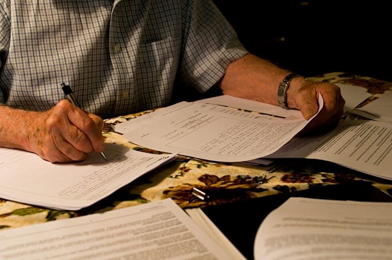 Older man working through bills and paperwork at a table
