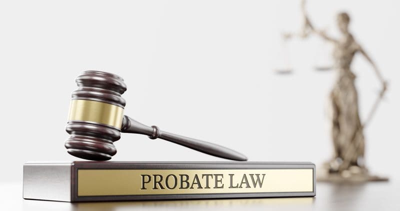 Judge's gavel on a nameplate reading Probate Law, with a statue of Justice behind it