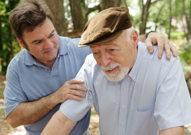 Adult son with his hands on his elderly father's shoulders