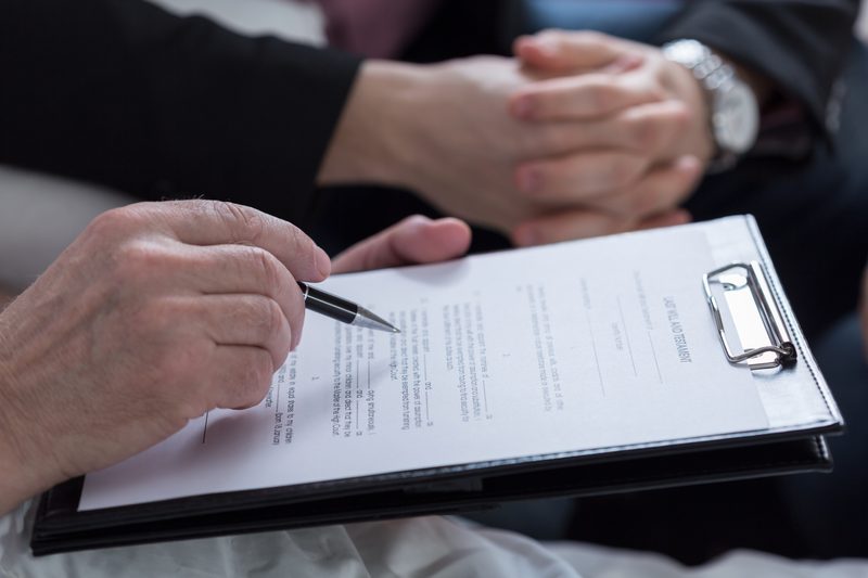 Older person signing a document on a clipboard